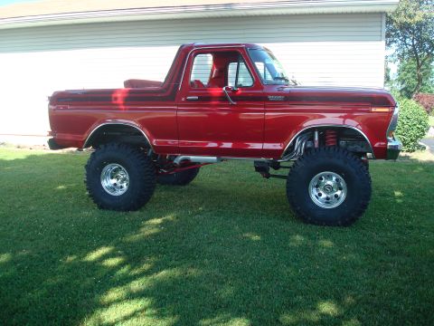 1978 Ford Bronco - This lifted red Ford Bronco has large off-road tires and custom exhaust pipes.