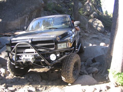 1989 Ford Bronco - Dodge Ram pickup truck tackling a challenging off-road course with large rocks.