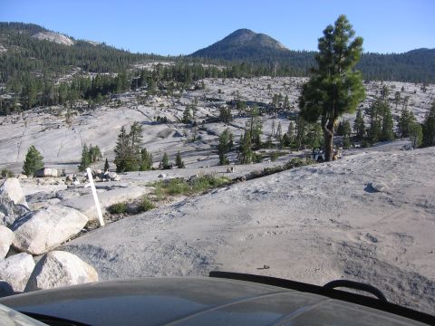 1989 Ford Bronco - A 1987 Ford Bronco is parked in a rocky, mountainous terrain with scattered trees under a clear blue sky.