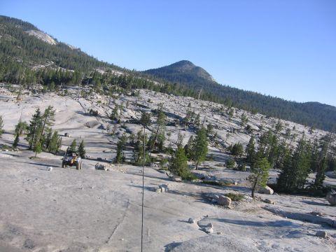 1989 Ford Bronco - An off-road vehicle is parked on a rocky, mountainous landscape under a clear blue sky.