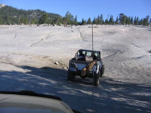 1989 Ford Bronco - An off-road vehicle navigates a cracked, rocky terrain under a clear blue sky.