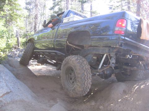 1989 Ford Bronco - This modified pickup truck is shown off-roading on a challenging dirt and rock path.