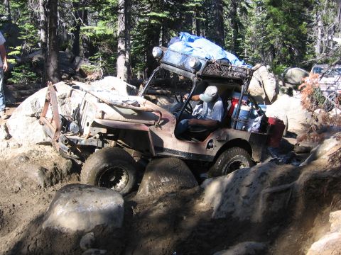 1989 Ford Bronco - Off-road vehicle struggling on a rocky, muddy trail with a person at the wheel.
