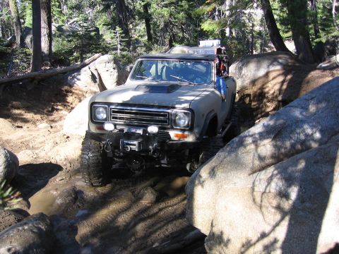 1989 Ford Bronco - This off-road vehicle is shown navigating a challenging trail with large rocks and mud.