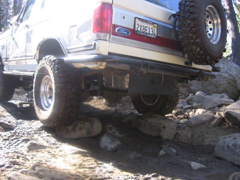 1989 Ford Bronco - 1989 Ford Bronco navigating rocky terrain, showing its rear end and spare tire.
