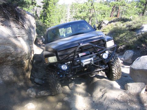 1989 Ford Bronco - Off-road truck carefully maneuvers through a challenging rocky terrain on a sunny day.