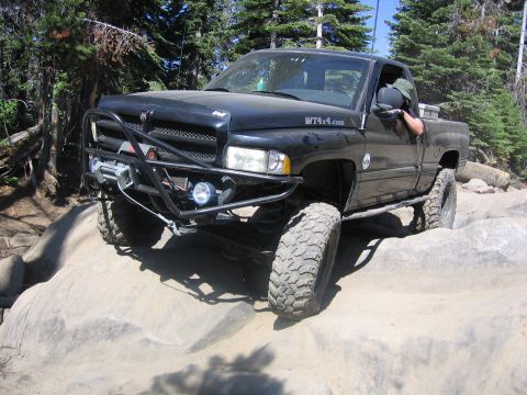1989 Ford Bronco - This black pickup truck, equipped with a winch and large off-road tires, navigates a rocky trail.
