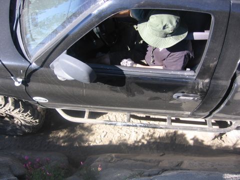 1989 Ford Bronco - Person in a green hat inside a black pickup truck, seen from the side.