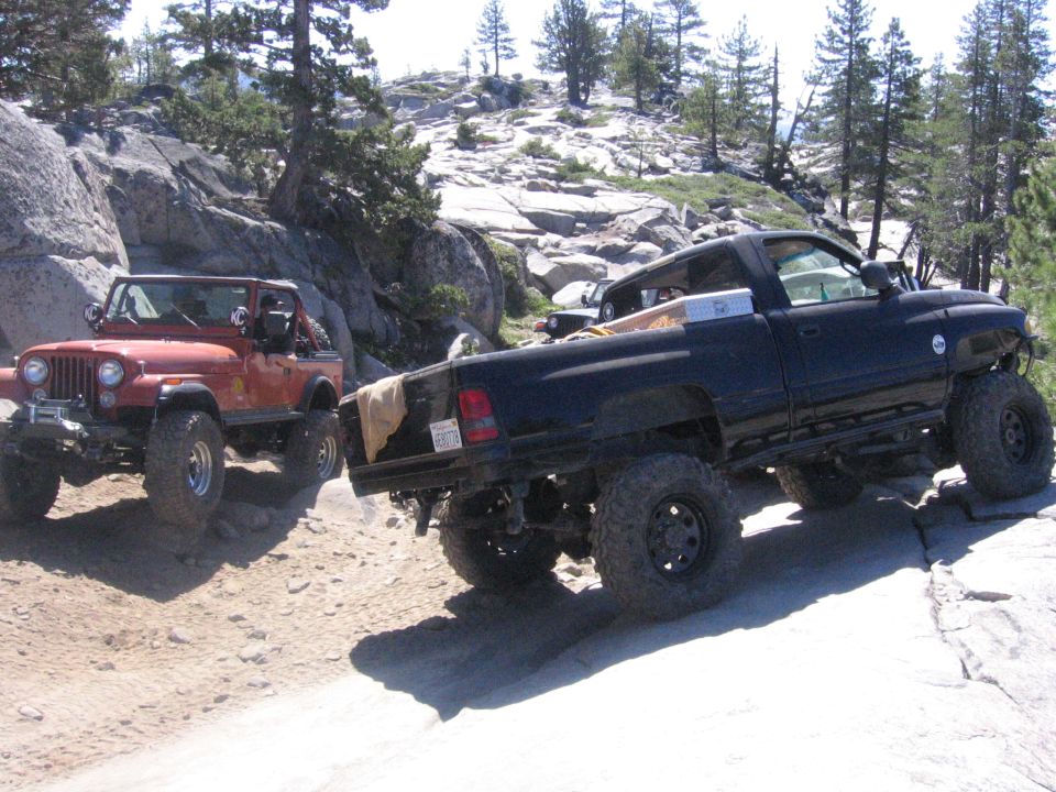 Black pickup truck and orange Jeep on rocky terrain