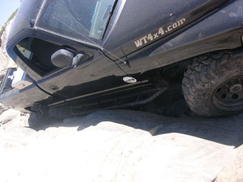 1989 Ford Bronco - A black SUV navigates a rocky terrain, its off-road tires gripping the uneven surface.