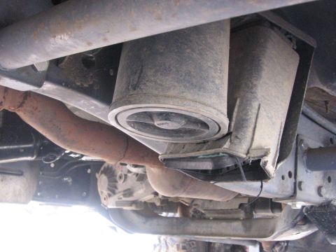 1989 Ford Bronco - Close-up view of the undercarriage of a vehicle, focusing on suspension components and exhaust piping.