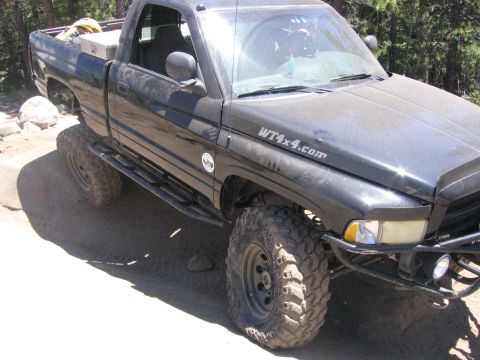 1989 Ford Bronco - A black pickup truck with "WT4x4.com" on the fender is parked on a dirt road with trees in the background.
