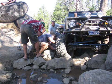 1989 Ford Bronco - People attempt to free a lifted 1978 Ford Bronco from rocks on an off-road trail.