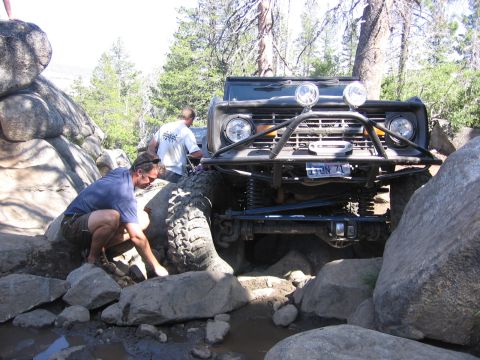 1989 Ford Bronco - A modified off-road vehicle is being carefully maneuvered over large rocks on a trail.