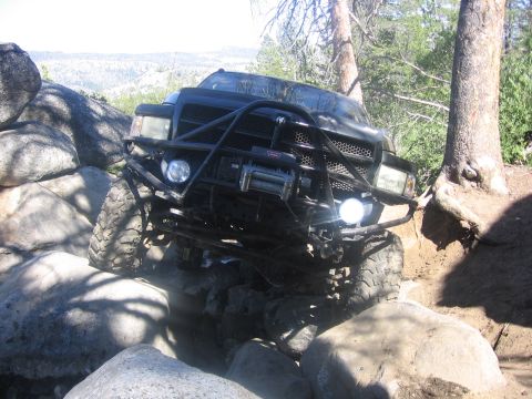 1989 Ford Bronco - Modified black truck with off-road tires and winch on a rocky trail.