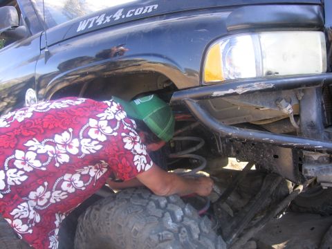 1989 Ford Bronco - Mechanic works on the suspension of a black truck, which has a WT4x4.com sticker on the fender.