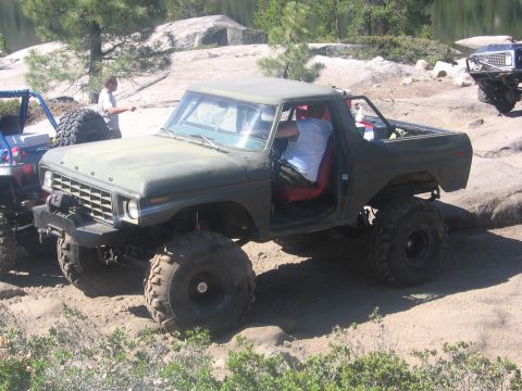 1989 Ford Bronco - An off-road vehicle navigates a rough terrain, with other vehicles visible in the distance.