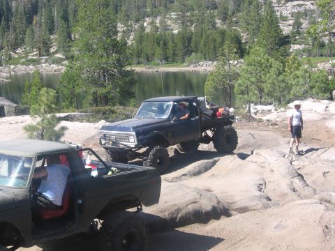 1989 Ford Bronco - A black 1989 Ford Bronco is seen off-road with another vehicle partially visible.