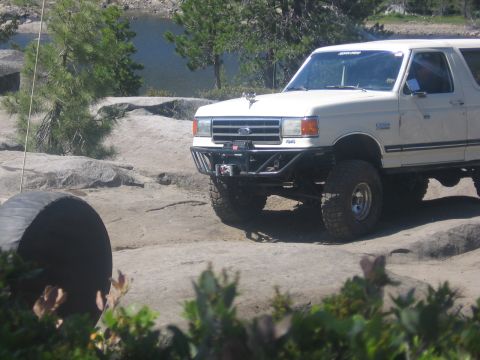 1989 Ford Bronco - A white SUV with large aftermarket wheels is seen from a 3q-front angle.