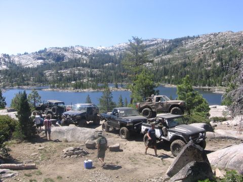 1989 Ford Bronco - Multiple off-road vehicles are visible at a campsite with a scenic mountain backdrop.