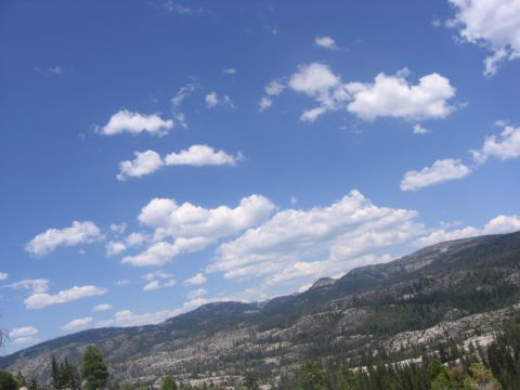 1989 Ford Bronco - A scenic view of a mountain range under a bright blue sky with fluffy white clouds.