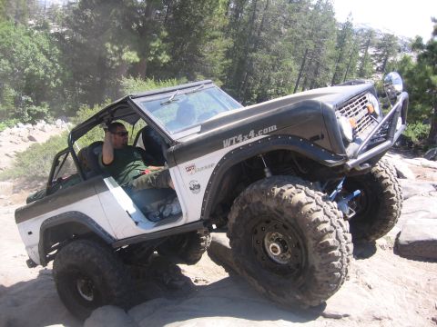 1989 Ford Bronco - This modified off-road vehicle is tackling a challenging rocky trail, with "WT4x4.com" visible on its side.