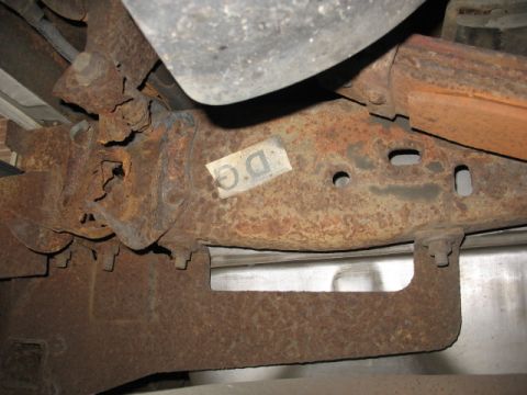1995 Ford C-350 (Centurion Conversions) - The underside of a vehicle shows significant rust on the frame and suspension parts, with a visible label.