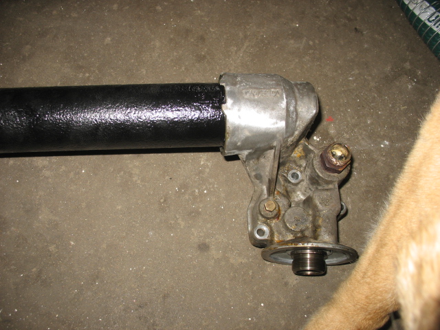 Oil cooler assembly with black pipe attached, resting on concrete floor