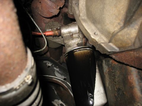1995 Ford C-350 (Centurion Conversions) - Close-up view of an oil filter with visible oil leakage, connected to engine components and exhaust system.
