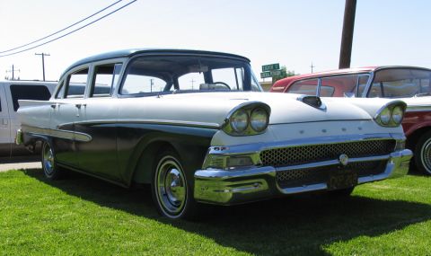 1984 Ford Bronco - This two-tone 1957 Ford Fairlane sedan is parked on a grassy area next to another vehicle.