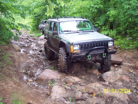 1979 Ford Bronco - A Jeep Cherokee XJ tackles a challenging rocky trail, with another vehicle visible in the background.