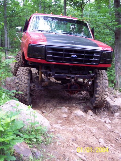 1979 Ford Bronco - A red Ford truck navigates a challenging off-road course with large tires and a lifted suspension.