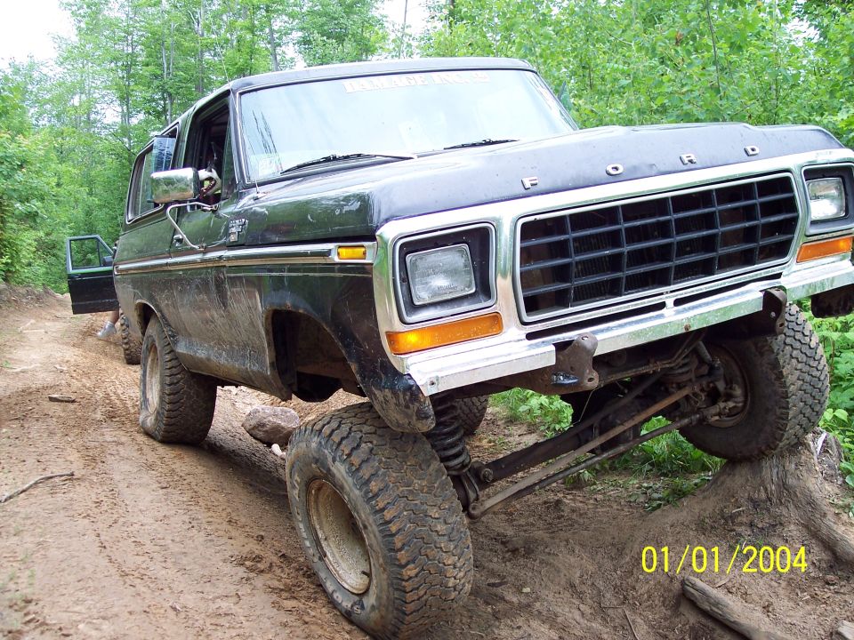 Black Ford Bronco with lifted suspension on a dirt trail, front passenger side wheel elevated