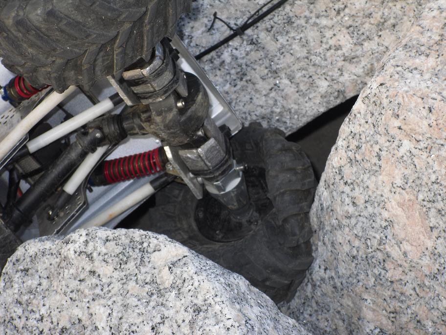 RC crawler chassis with suspension and tire wedged between rocks