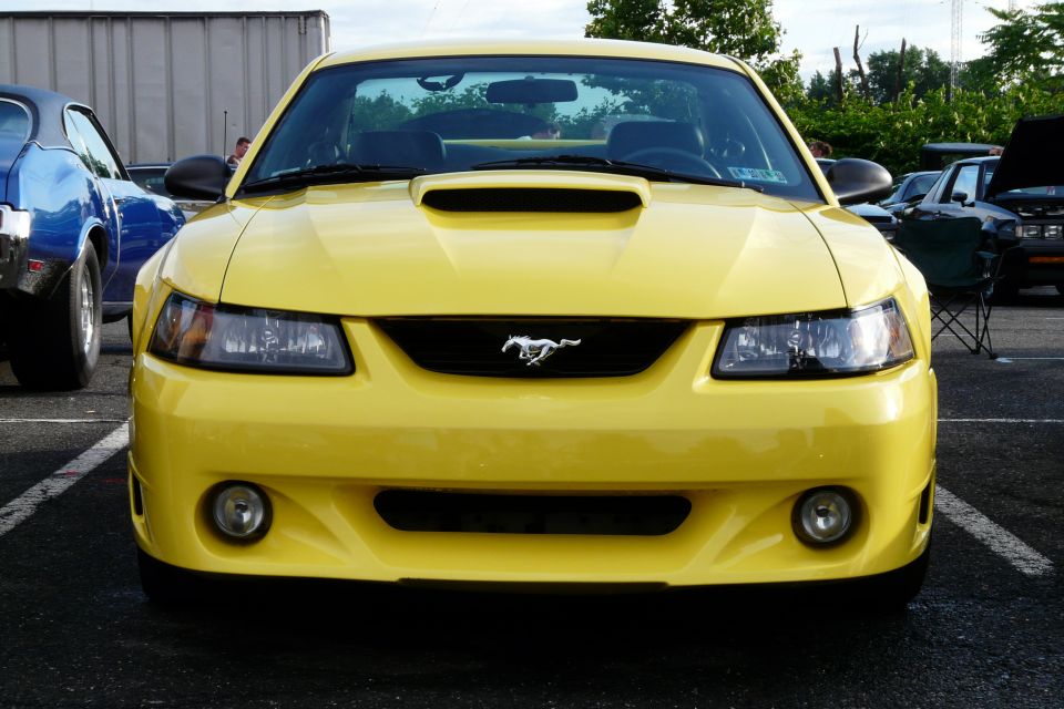 Yellow 2002 Ford Mustang front view with a blue car to the left