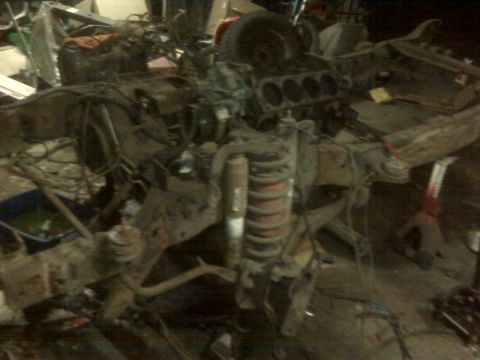 1995 Ford Bronco - This image shows a disassembled vehicle chassis, likely undergoing repair or restoration, with the engine block and suspension parts promin…