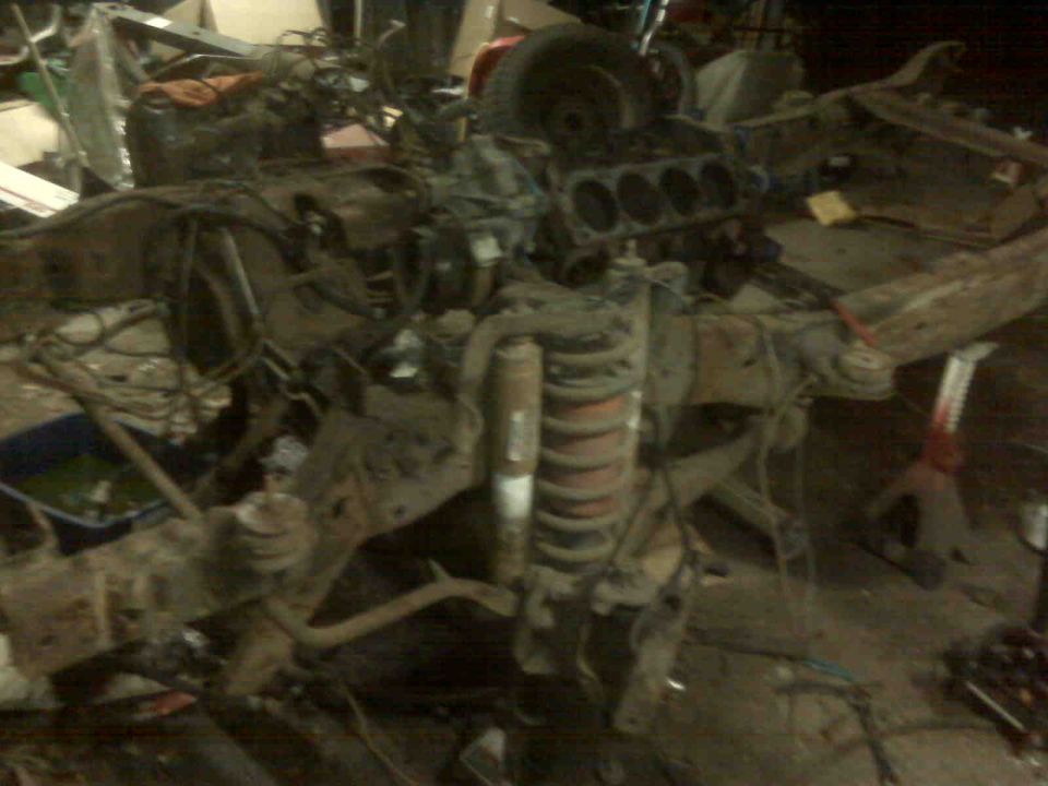 Disassembled vehicle chassis with engine block and suspension components visible