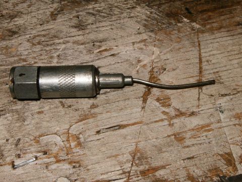 2000 Ford E350 - Close-up of a metal grease gun component on a weathered wooden background.