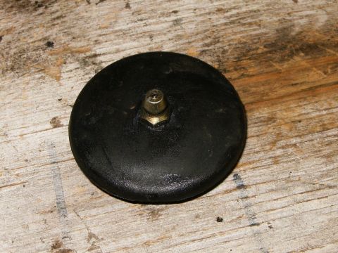 2000 Ford E350 - A black round part, possibly a cap or cover, with a central metal fitting is shown on a wooden surface.
