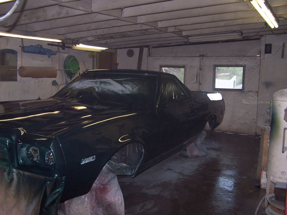 Dark green Ranchero body on stands in a home paint booth after fresh paint, trim removed