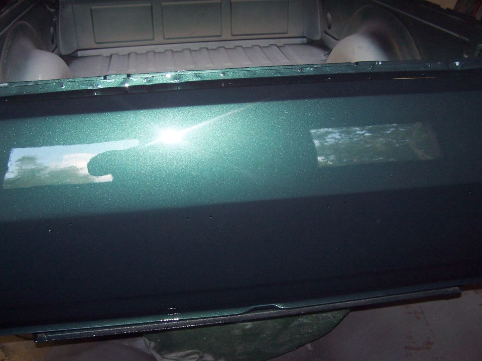 Metallic teal-green painted tailgate panel with glossy finish in front of pickup bed