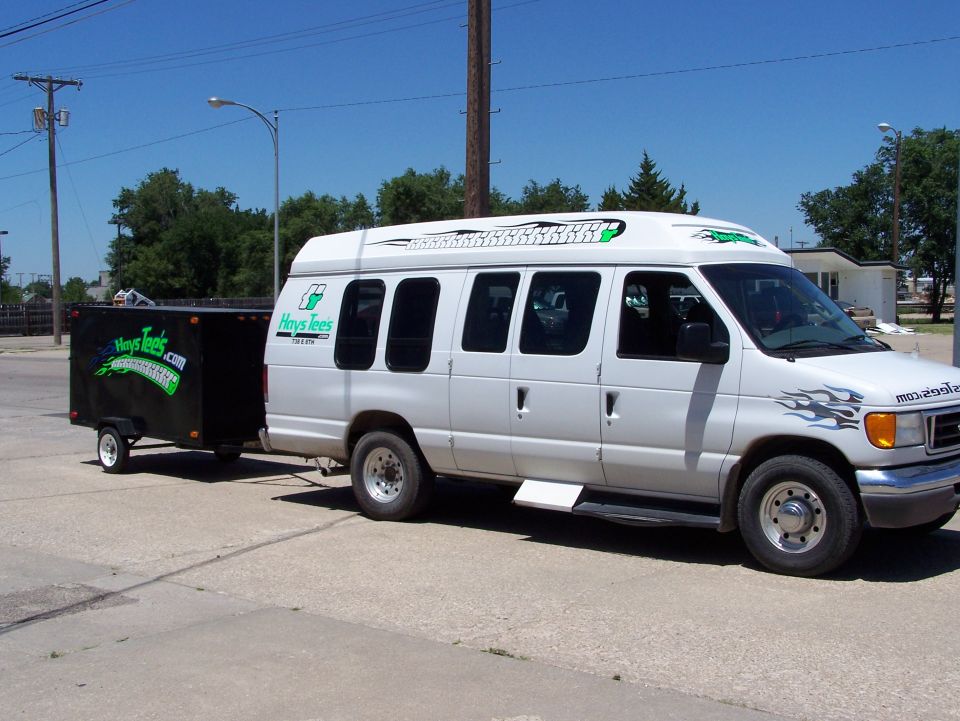 White van with flame decals and a black trailer with green lettering