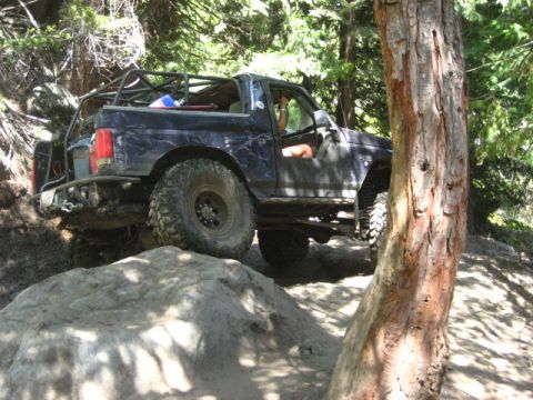 1989 Ford Bronco - This modified SUV navigates a challenging rocky trail, demonstrating its off-road capabilities.