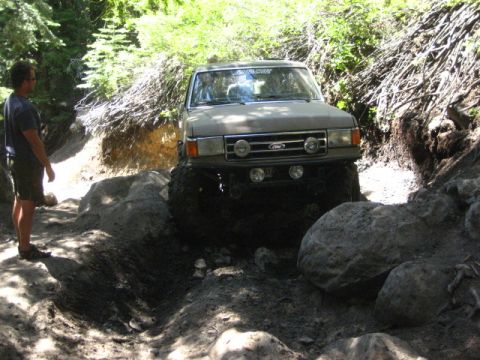 1989 Ford Bronco - Ford Bronco tackling a challenging off-road obstacle course on a sunny day.