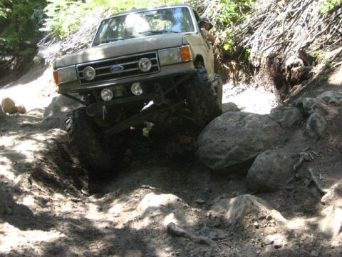 1989 Ford Bronco - This modified Ford Bronco is tackling a challenging off-road obstacle on a sunny day.