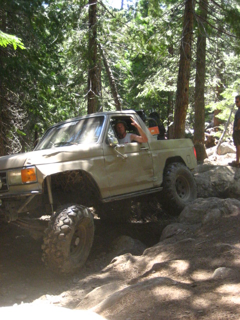 1989 Ford Bronco - Driver of a tan 1989 Ford Bronco navigates a challenging rocky trail during an off-road excursion.
