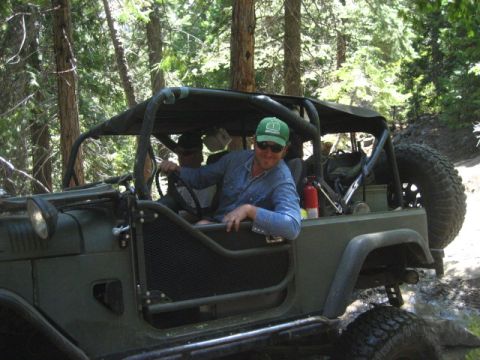 1989 Ford Bronco - Driver of an off-road vehicle navigates a trail in a forest setting.
