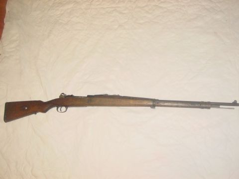 1979 Ford Bronco - A long rifle with a wooden stock and metallic barrel is displayed against a textured white background.