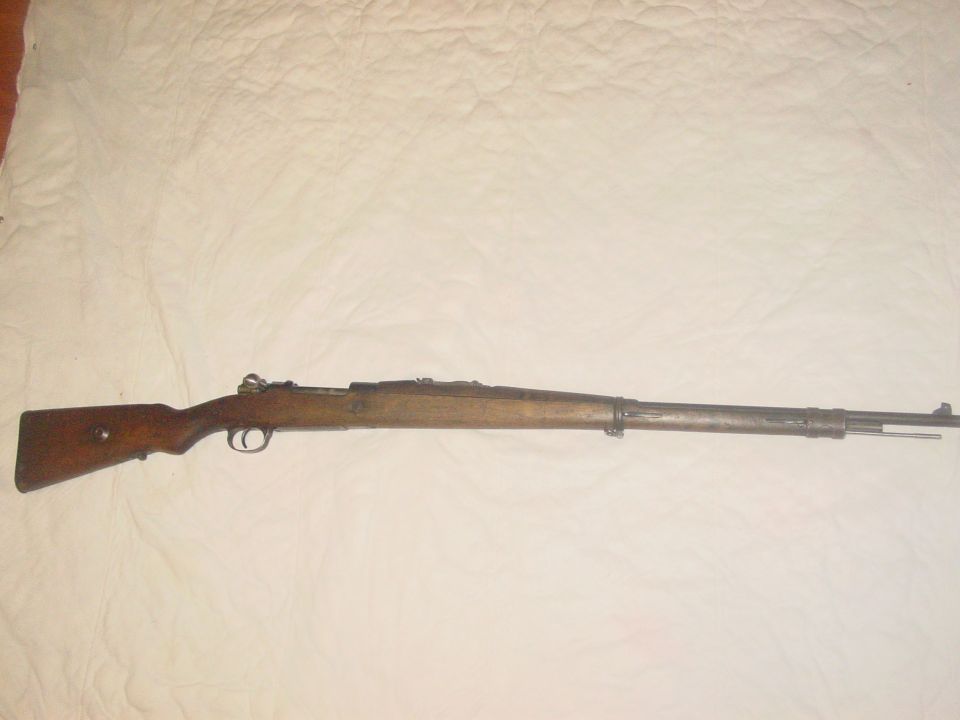 Bolt-action rifle with wooden stock and metal barrel, laid out horizontally