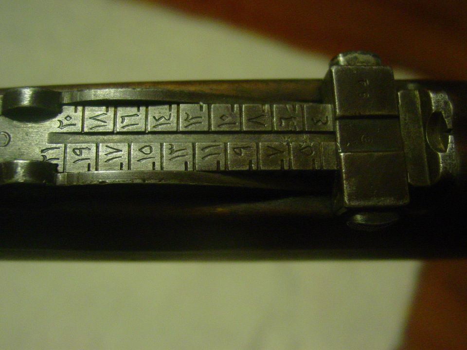 Close-up of a gun's rear sight with Arabic numerals and markings